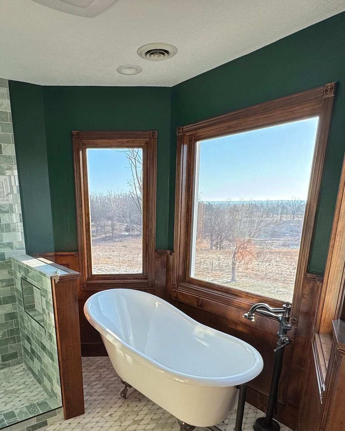 The same bathroom bay with the wainscot and window casings stained, and a freestanding tub in front