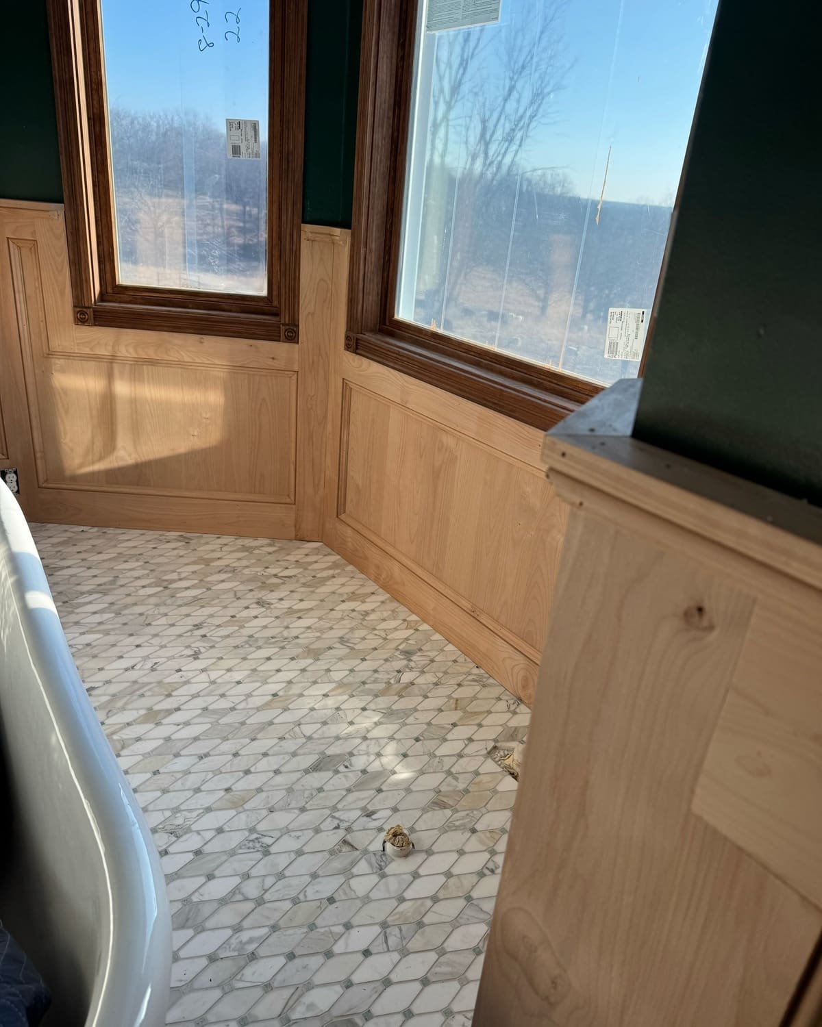 Unfinished raised-panel wainscot around a bathroom bay window, before staining