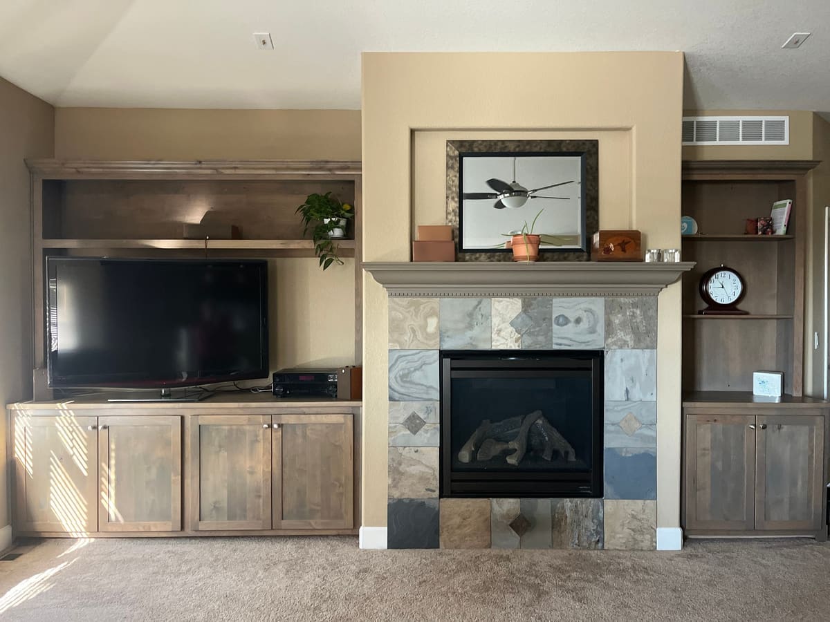 Stained shaker-style built-ins on both sides of a tiled fireplace: a media base on the left, a bookcase on the right
