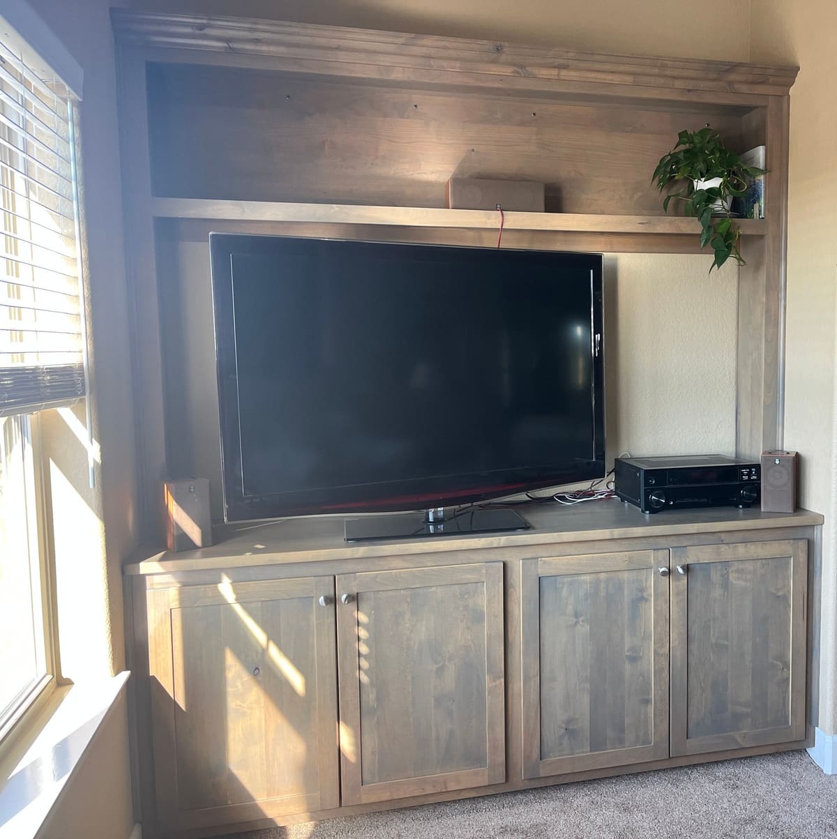 Gray-stained media built-in with four shaker doors, an open TV bay and a crowned upper shelf