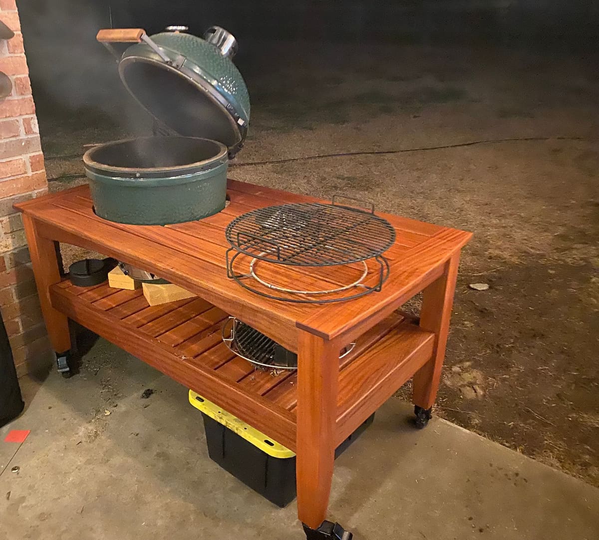 Reddish hardwood kamado grill cart with slatted top and lower shelf on locking casters