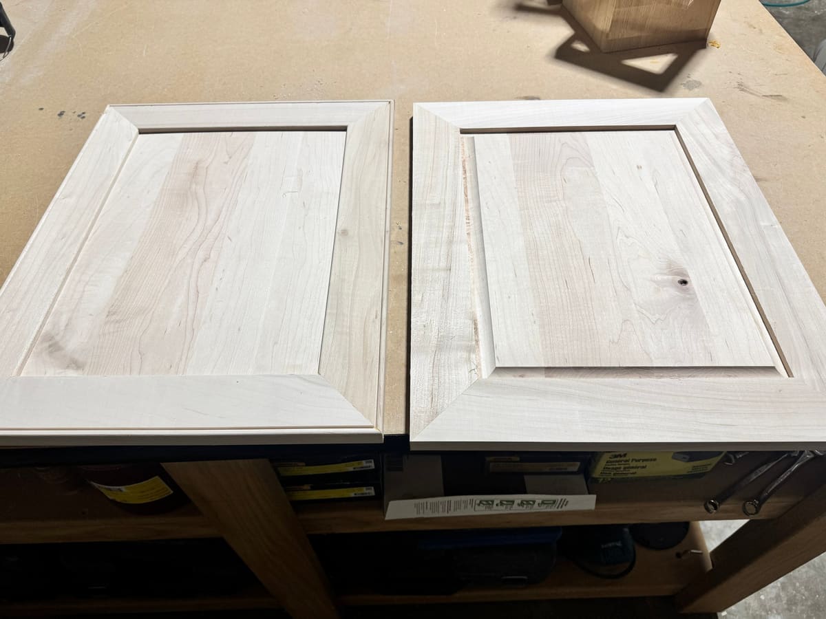 Two unfinished cabinet doors with mitered frames laid side by side on a shop bench