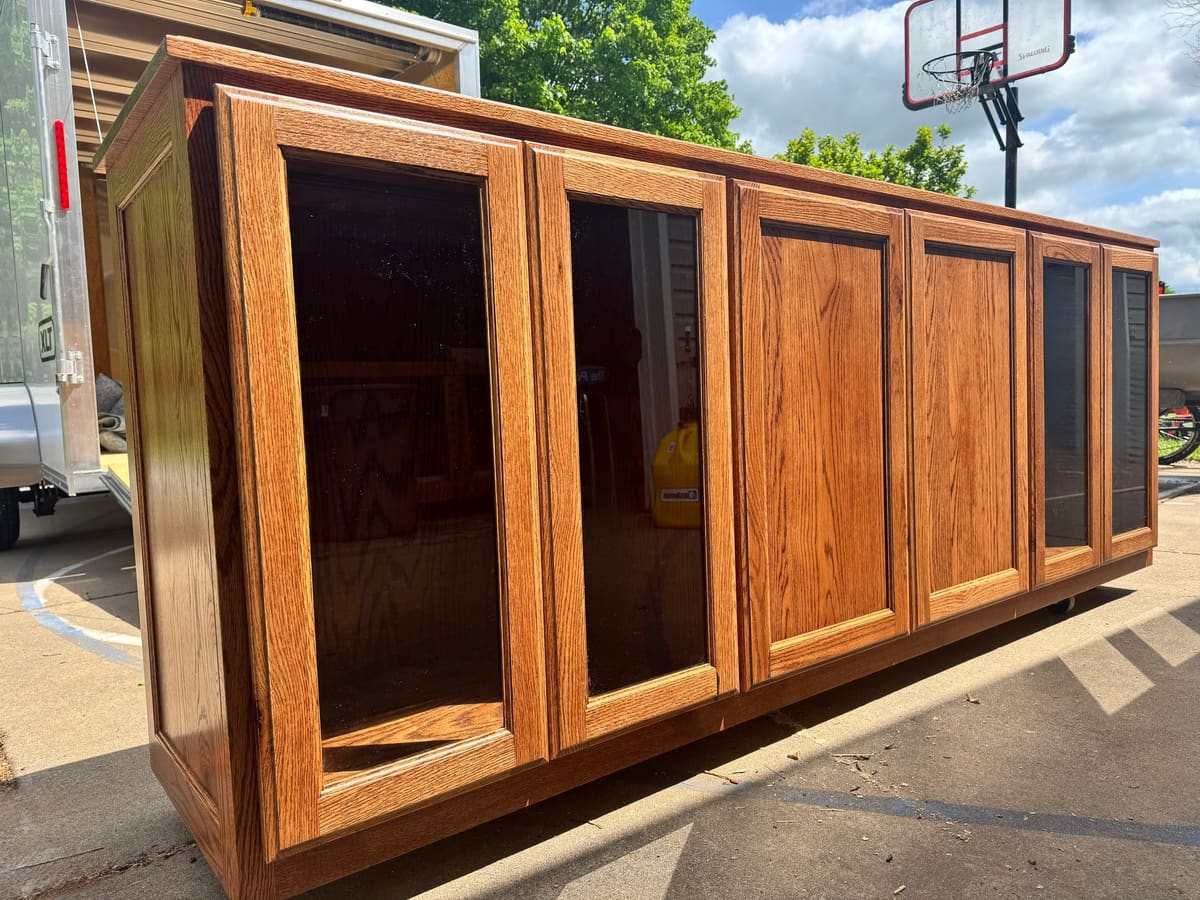 Long cabinet with glass-front and flat-panel doors in a golden stain, photographed outdoors