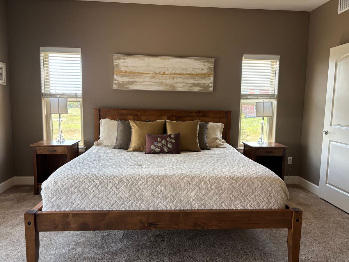 King bed with a wood panel headboard and footboard flanked by matching one-drawer nightstands