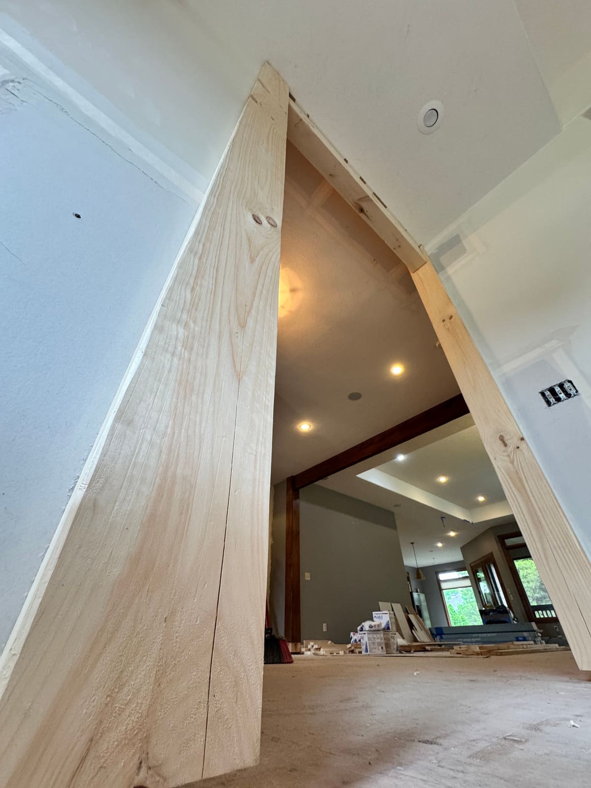 Low angle view of a wide opening wrapped in unfinished pine boards during a remodel, dark beams beyond